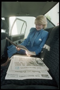 Margaret Heckler, United States Ambassador to Ireland, reading newspaper in the back of a limousine