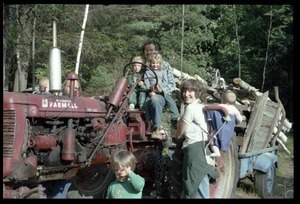 Dan Keller pulling a load of wood behind a tractor, beset by children, Montague Farm commune
