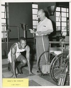 Ted Corbitt crouched in front of a man with a stopwatch