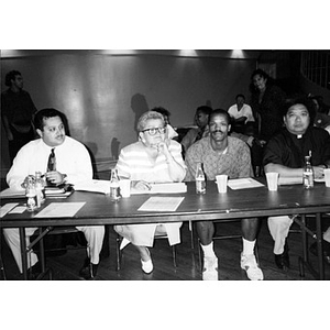 Three men and one woman at a table during a community meeting.