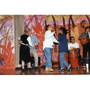 Students and teachers dancing on stage during a music and dance program organized by Inquilinos Boricuas en Acción's Areyto program.