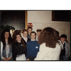 A woman, facing away from the camera, stands in front of a group of boys and girls at the "Recognition Dinner at Harvard Club"