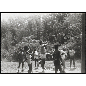 Two youth leaping up during a volleyball game while their teammates look on