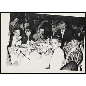 A man and boys sit at a table during a dinner