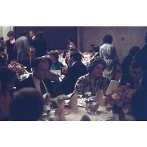 People seated at dinner tables review menus during a formal banquet event