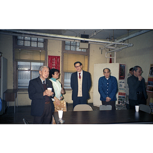 Several adults, with You King Yee at the center right, gather around a table chatting at a Chinese Progressive Association event