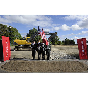 Four ROTC cadets stand with flags on the groundbreaking site for the George J. Kostas Research Institute for Homeland Security