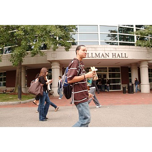 Torch Scholar Odalis David Polanco eats a sandwich as he walks past Shillman Hall