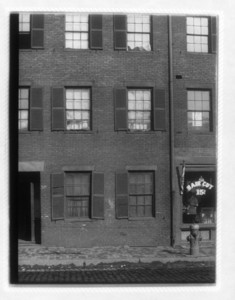 View of a building housing a barbershop on the right and a drainpipe in the center, probably on Dorchester Ave.