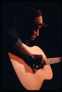 Mississippi John Hurt: studio portrait, seated, playing guitar