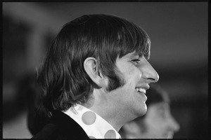 Ringo Starr seated at a table during a Beatles press conference: close-up in profile