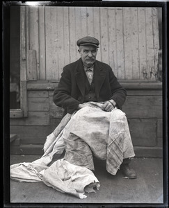 Capt. Fred Hutchins of Bucksport, who was tied up with his wife in houseboat at South Station: Hutchins seated with a cloth on his lap