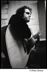 Tim Hardin smoking a cigarette and playing guitar at the Unicorn Coffee House, Boston, Mass.