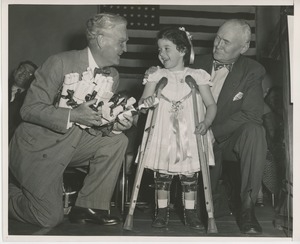 Bruce Barton handing diploma to young girl wearing braces and crutches