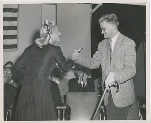 Margaret Milbank Bogert presents a small book to a man using a cane