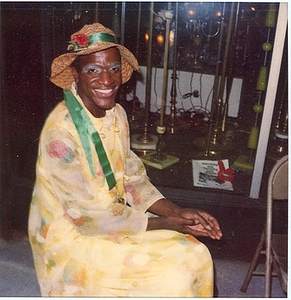 A Photograph of Marsha P. Johnson Wearing a Yellow Floral Dress and a Patterned Orange Hat