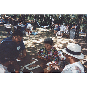 People play dominoes at a card table during a picnic event