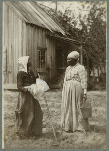 Two black women chatting at the garden by a house