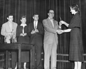 A student presents an award to Director of Student Affairs Director John V. Colburn at Suffolk University's Recognition Day ceremony, circa 1953