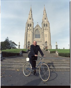 Cardinal Tomas O'Fiaich, Catholic Primate of all Ireland on his bicycle outside Armagh Cathedral