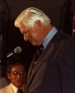 Side shot of Thomas P. O'Neill speaking at a microphone with head bowed