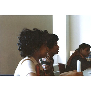 Three Hispanic American teenagers seated in a classroom, listening