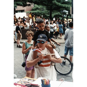 Man with a young boy on his shoulders stops by a booth at Festival Betances.