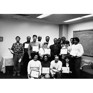 Group portrait of adults holding framed certificates.