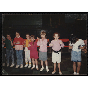 Several Boys and Girls Club members do the chicken dance in an auditorium