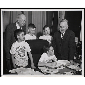 Mayor John B. Hynes and Executive Director of Boys' Clubs of Boston Arthur T. Burger pose with boys at a desk