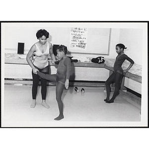 A dance instructor shows a girl how to lift her leg