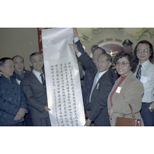 Henry Wong and a member of the delegation from Guangdong Province hold up a banner with Chinese inscription as others stand around them
