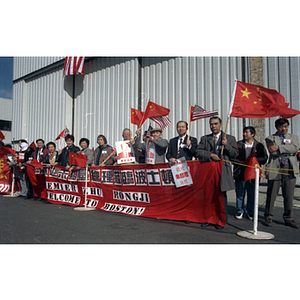 People hold flags and posters for an event at Boston Logan Airport to welcome Zhu Rongji, Premier of the People's Republic of China