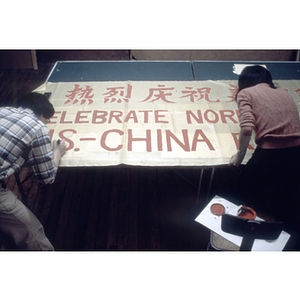 Two people painting a banner