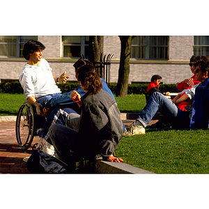 Students sitting on the grass and socializing on campus