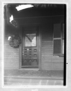 Close up of the door of a house, with a Merry Christmas banner displayed in the window of the door
