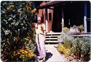 Sandi Sommer at front entrance of Salmon Creek house, beside sunflowers