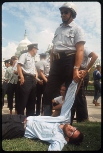 Police arresting a prone antiwar protester, with the Capitol dome in the background: Washington Vietnam March for Peace