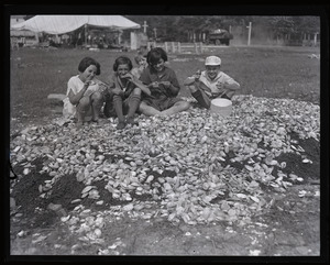 Children gathered around of heap of clamshells