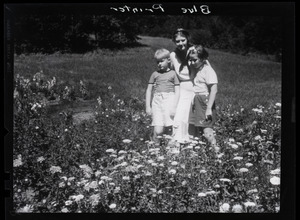 Dorothy Thompson, her son Michael Lewis, and unidentified girl standing in a field of flowers