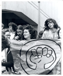 Board of Trustees fee increase demonstration: student holding sign with hand-painted fist