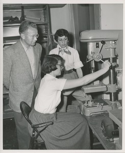 Occupational therapist demonstrating a drill press for two unidentified onlookers