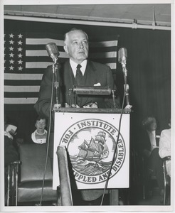 Unidentified man speaking behind podium at Institute Day