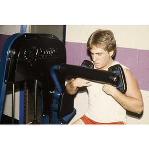 Man works out on a weightlifting machine in a gym