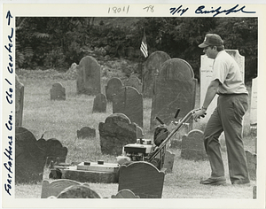 Cemetery employee John Sousa Jr. cuts between tombstones