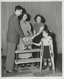 Four disabled young people pointing out their home countries on a globe