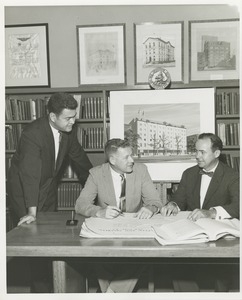 Willis C. Gorthy signing paperwork at a presentation of prospective building plans