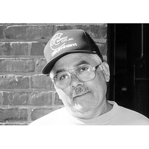 Portrait of a man wearing glasses and a baseball cap.