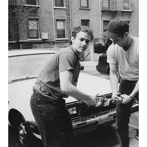Inquilinos Boricuas en Acción staff member Erik Blanchard (right) and an unidentified teen wringing out a rag in a parking lot.
