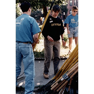 Volunteers take rakes from a large pile in order to start in on a community clean-up effort.